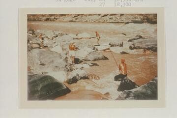 Nevills crew lining Vulcan Rapid. Nevills stands on the skiff; Milotte tries for a picture from left; Frost strains on the painter; Joe Desloge struggles in the water at right