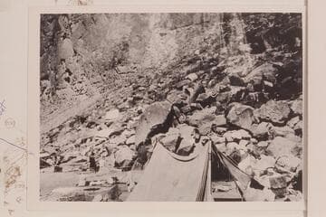 Eddy's boat "Powell" rolled on shore after capsizing when being lined at the head of The Big Drop. Note food and clothing out to dr. From the Carey collection