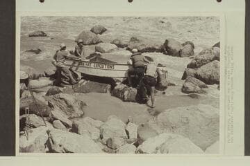 Georgie White, second from right, assisting the Wright-Rigg crew in the portage of Vulcan Rapid. Paul Wright appears in the margin of the print at the left. Frank Wright is on the near side of the stern, and Jim Rigg is under the bow