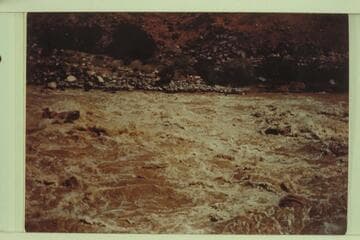 Motorboat just past the wave at the head of Lava Falls and cutting to the left to avoid the holes at the right of the picture. Marston, Desloge, and Taylor in the boat